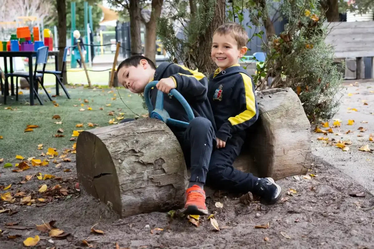 Two boys are playing on a log with a wheel