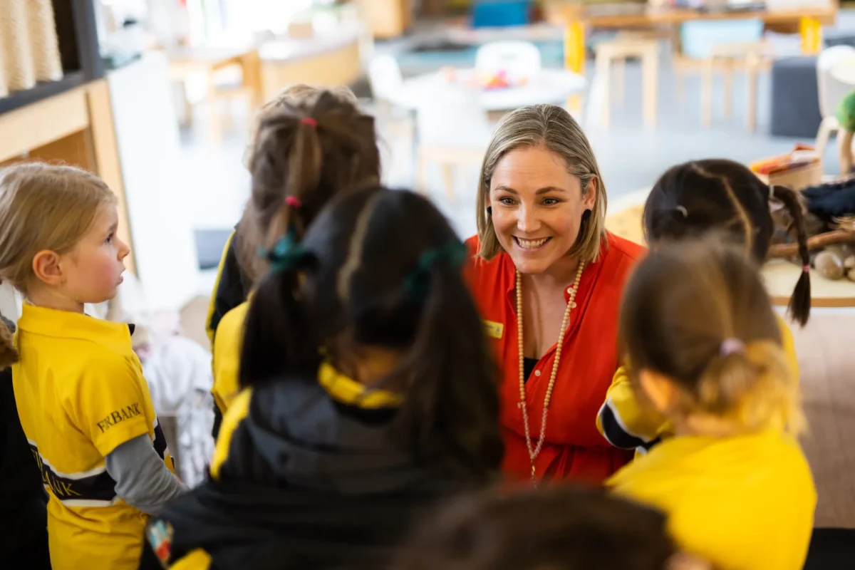 A female teacher in a red outfit with her students
